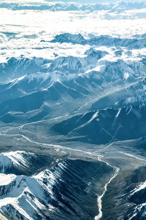 積雪的山峰聳立於雲層之上，河谷蜿蜒穿過地形。