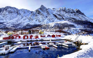 白雪覆蓋的漁村，紅色小屋，冰封港口，群山環繞 — 2560x1600 壁紙