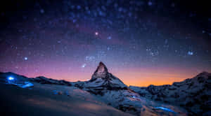 星空暮色天空下的白雪覆蓋的山峰，下方有發光的藍色燈光。 — 星星 壁紙
