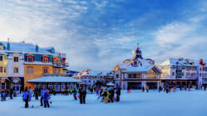 冬季場景，人們在黃昏時分在白雪覆蓋的城鎮廣場上滑雪和玩滑雪板。 — 雪山 壁紙
