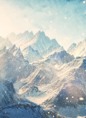 在淡藍色的天空下，白雪覆蓋的山脈飄落著雪花。 — 山脈 壁紙