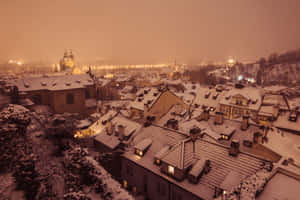 夜間歷史小鎮中，白雪覆蓋的屋頂與發光的窗戶。 — 冬季風景 壁紙