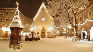 夜晚白雪覆蓋的城鎮廣場，閃爍的燈光和教堂。 — 冬季美學 壁紙