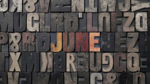 復古木製活字塊拼出 june，帶有磨損質感。 — 六月 壁紙
