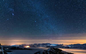 積雪的山峰下，星空燦爛的夜空，山谷燈光閃爍。 — 暮光 壁紙