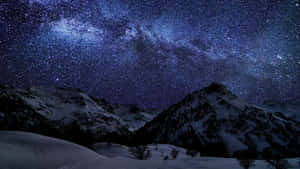 在鮮豔的星空下，積雪的山峰和可見的銀河。 — 筆電 壁紙