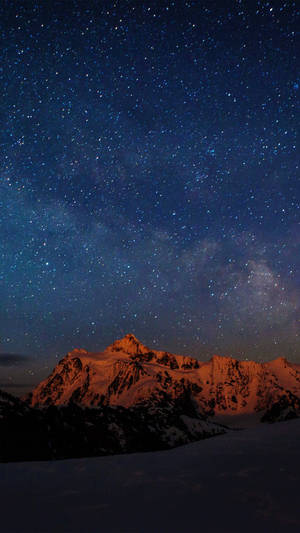 繁星點點的夜空下的積雪山脈，銀河可見。 — 夜晚 壁紙