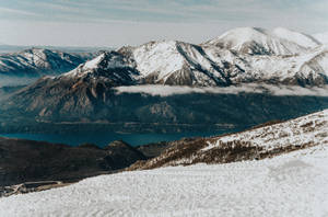 積雪的山脈下方有藍色湖泊，雲霧在山谷中飄蕩。 — 阿根廷 壁紙