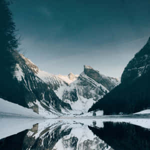 黃昏時分，積雪的山峰倒映在冰凍的湖面上。 — 冬季風景 壁紙