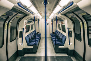 空曠的地鐵車廂，配有藍色圖案座椅和頭頂扶手。 — 地鐵 壁紙