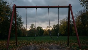 多雲天空下，黃昏時分落葉公園中的空紅色鞦韆架。 — 憂鬱 GIF 壁紙