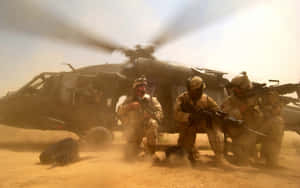 穿著沙漠裝備的士兵在沙地環境中蹲在軍用直升機附近。 — 藍天 壁紙