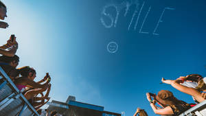 節日人群觀看無人機在天空寫下「SMILE」。 — 慶祝 壁紙