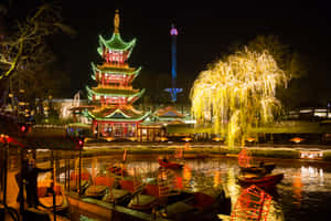 節日夜景，發光的寶塔和柳樹倒映在運河中，伴有船隻。