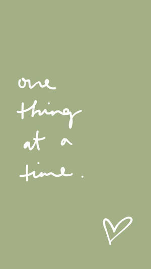 白色手寫語錄「one thing at a time」在鼠尾草綠色背景上，附小心形。 — 動力 壁紙