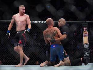 MMA拳手勝利站立，裁判停止比賽，對手在籠中跪地敗陣。 — 終極格鬥冠軍賽 壁紙