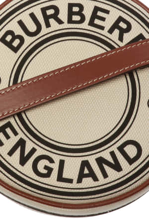 Burberry England 標誌手提包，搭配棕色皮革肩帶和白色縫線。 — Burberry 壁紙