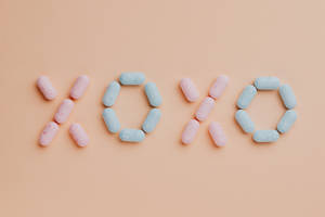 藥丸在桃色背景上拼出 XOXO — 可愛又粉嫩 壁紙