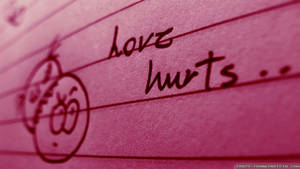 粉紅色橫線紙上以手寫文字「love hurts」和塗鴉的悲傷臉孔。 — 夜空 壁紙