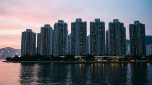 黃昏時分的城市天際線，發光的塔樓倒映在水中 — 香港 壁紙