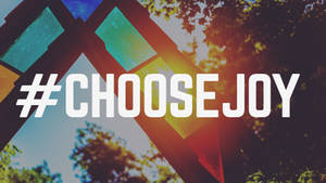 彩繪玻璃結構，背景有樹木和陽光，前方是粗體文字 hashtag choosejoy — 喜悅 壁紙