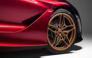 紅色光面McLaren 720S跑車，配金色輪圈，在攝影棚燈光下。