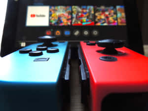 紅色和藍色 Nintendo Switch 控制器對焦，後面有遊戲畫面。 — 酷炫遊戲 壁紙