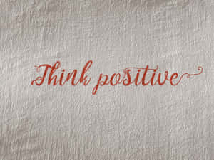 紅色閃粉草書文字寫在帶紋理的銀色牆上，內容為「Think positive」 — 正向 壁紙