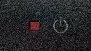 黑色紋理表面上的紅色電源按鈕，帶有白色電源符號。 — 光線 壁紙