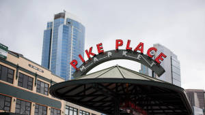 陰天下背景有玻璃塔的Pike Place Market標誌 — 2560x1440 壁紙
