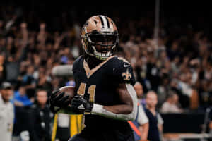 美式足球員夜間在球場帶球奔跑。 — Alvin Kamara 壁紙