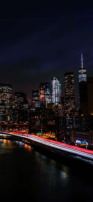 紐約天際線的夜景，建築物燈火通明，交通燈光形成光軌。 — POCO C 壁紙