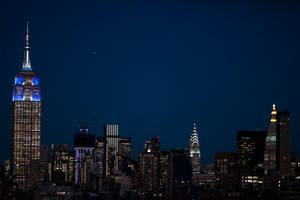 紐約市夜景天際線，摩天大樓燈火通明，黑暗天空中可見一顆星星。 — 帝國大廈 壁紙