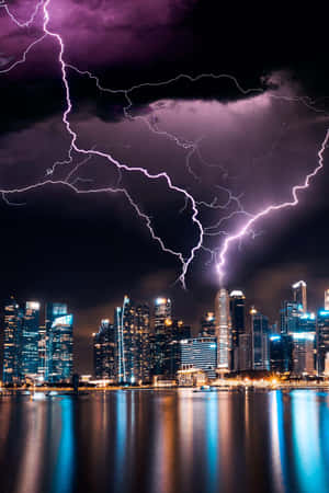 紫色閃電照亮了倒映在水中的現代城市夜景天際線。 — 閃電麥坤 壁紙