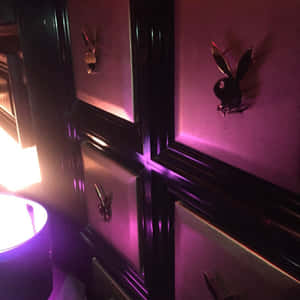 紫色霓虹燈在昏暗的房間中突顯了黑色框架面板上的Playboy兔子標誌。 — 花花公子 GIF 壁紙