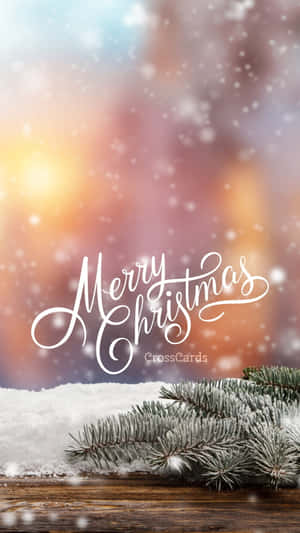 結霜的松樹枝在雪白的木頭上，帶有「Merry Christmas」文字，背景是溫暖的日落散景。 — 聖誕節手機 壁紙