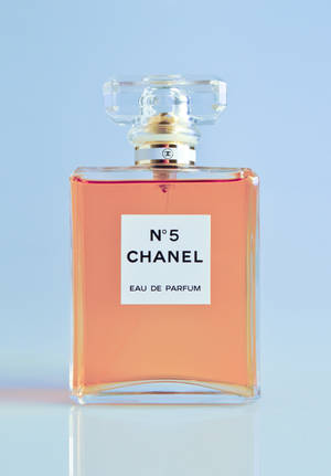 Chanel No 5 香水瓶，裝有桃色液體，置於反光表面上。 — OnePlus Pad 3 壁紙