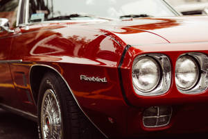 經典紅色亮面 Firebird 肌肉車，帶有鍍鉻飾邊和圓形頭燈。 — 跑車 壁紙