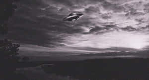 UFO在多雲天空下盤旋在黃昏的黑暗景觀之上。 — 太空船 壁紙