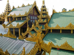 金色寺廟屋頂，帶有精緻的尖頂和青綠色瓦片，在晴朗的天空下。 — 曼谷 壁紙