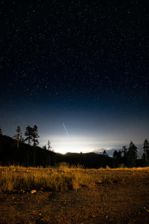繁星點點的夜空，流星越過山脈和樹木 — 夜晚 壁紙