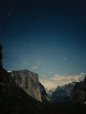 一顆流星劃過繁星點點的夜空，越過積雪的山脈和黑暗的森林。 — 丘陵景觀 壁紙