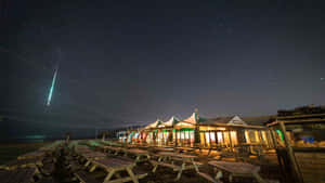 流星劃過海灘野餐區和帳篷上方的星空夜空。 — 美麗的夜晚 壁紙