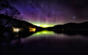 北極光在夜晚的星空湖上閃耀，山巒剪影。 — 蘇格蘭 壁紙
