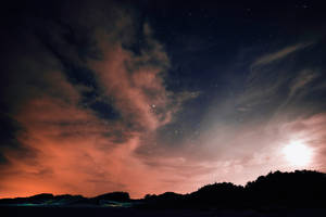 繁星點點的夜空，橙雲和月亮，在黑暗的山丘上方。 — 夜晚 壁紙