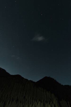 繁星點點、薄雲輕飄的夜空下，黑暗森林覆蓋的山巒。 — Huawei MatePad Edge 壁紙