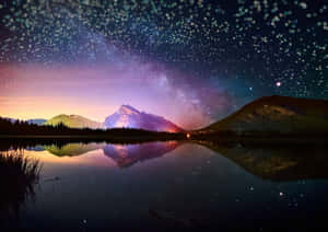 繁星點點的夜空，銀河在雪山上空，倒映在平靜的湖面上。 — 暮光 壁紙