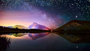雪覆山巒在星空下倒映在夜晚平靜的湖面上。 — 日落 壁紙