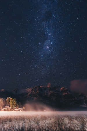 星空下積雪的山巒，下方是冰凍的湖泊。 — 暮光 壁紙