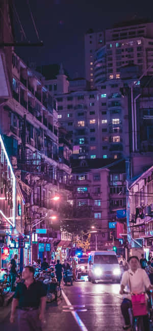 夜晚的城市街道，有發光的霓虹燈招牌和行人。 — iPhone Xs Max 壁紙